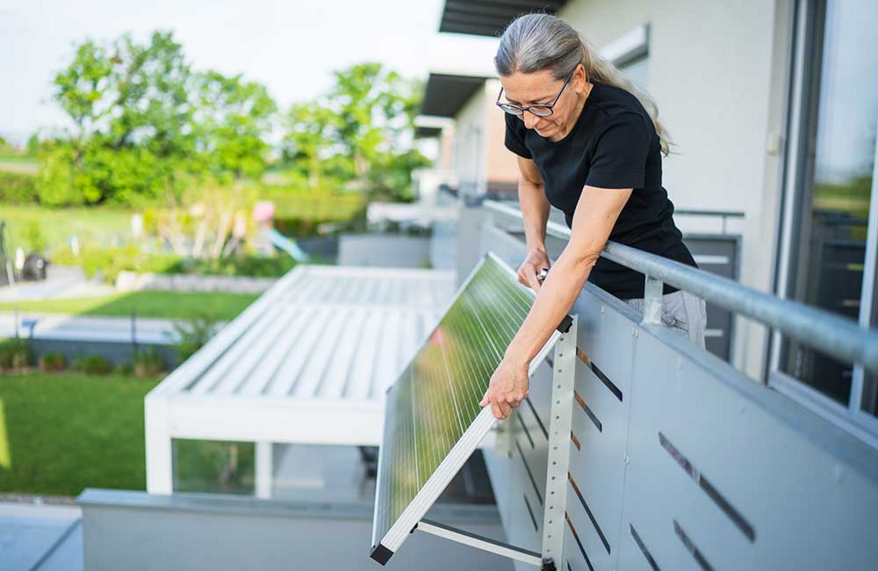 Frau installiert ein Balkonkraftwerk. Frau_installiert_Solarpanel.jpg
