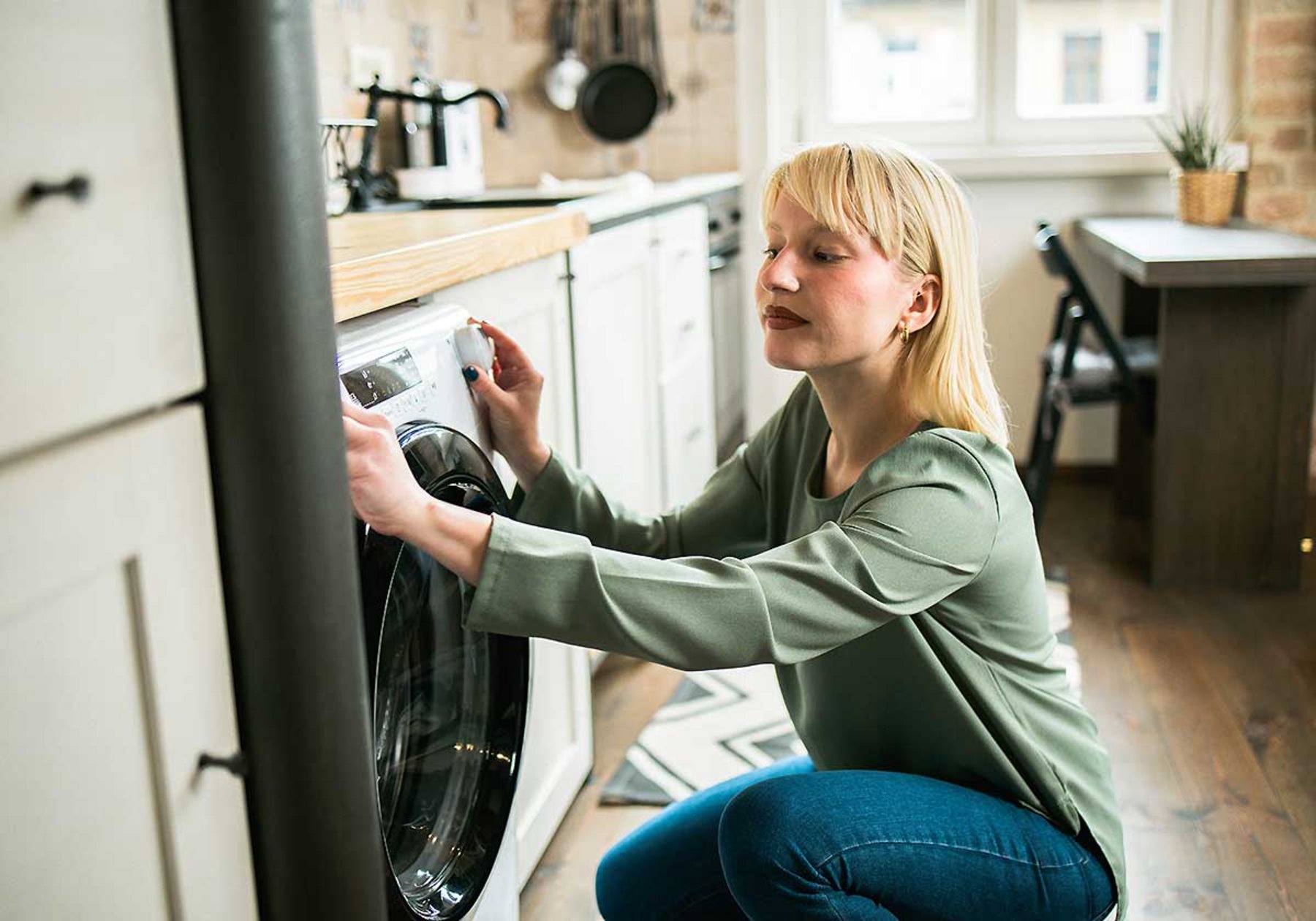 Eine Frau macht ihre Waschmaschine an Single_Haushalt_Stromverbrauch.jpg