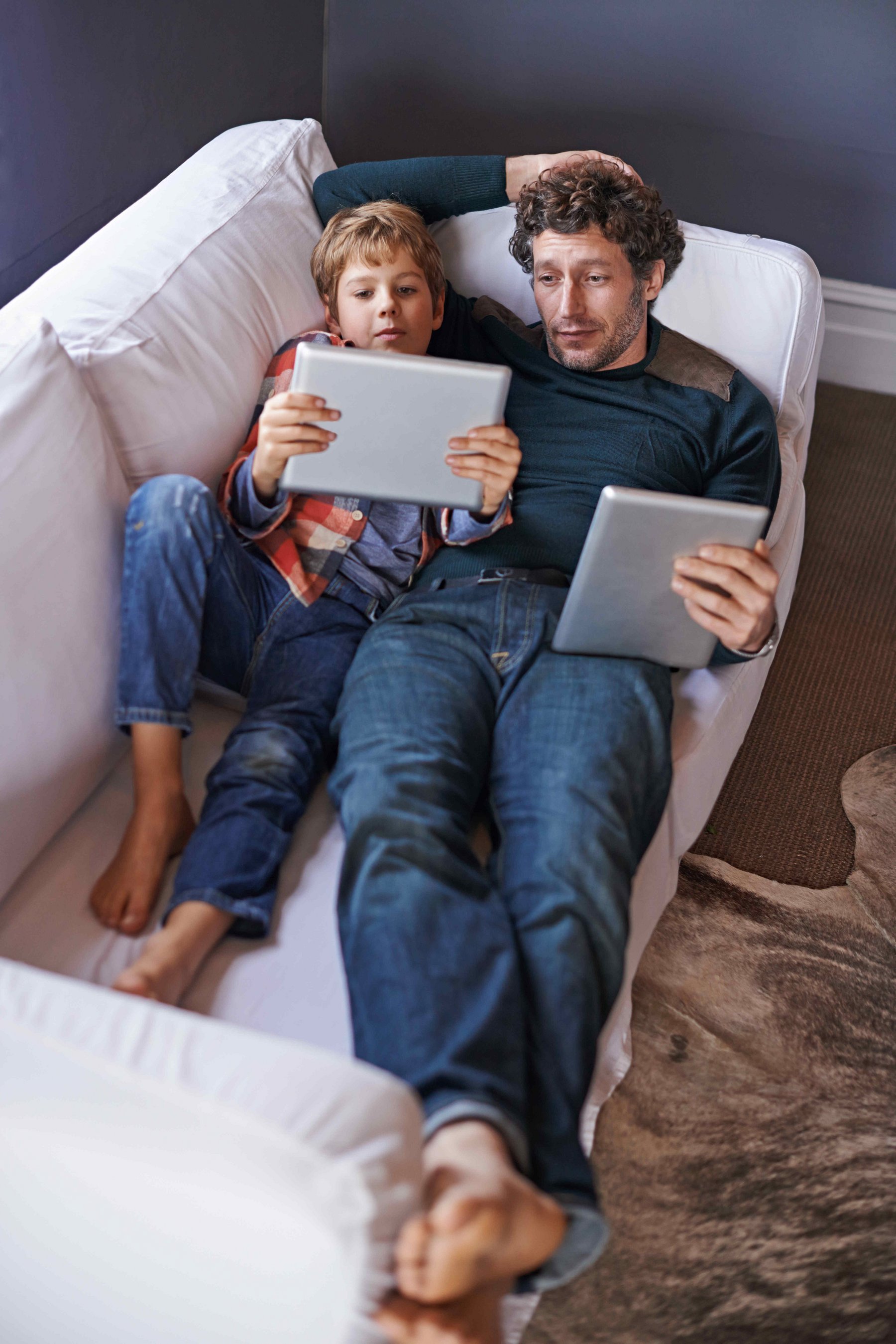 Vater und Sohn mit Tablets auf dem Sofa AdobeStock_764102763.jpeg